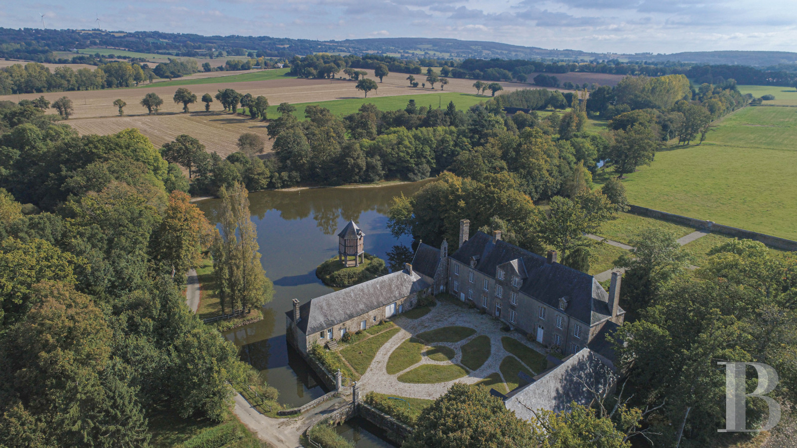 En Mayenne, au nord de la ville éponyme, un château du 17e siècle ceinturé de douves en eau - photo  n°1
